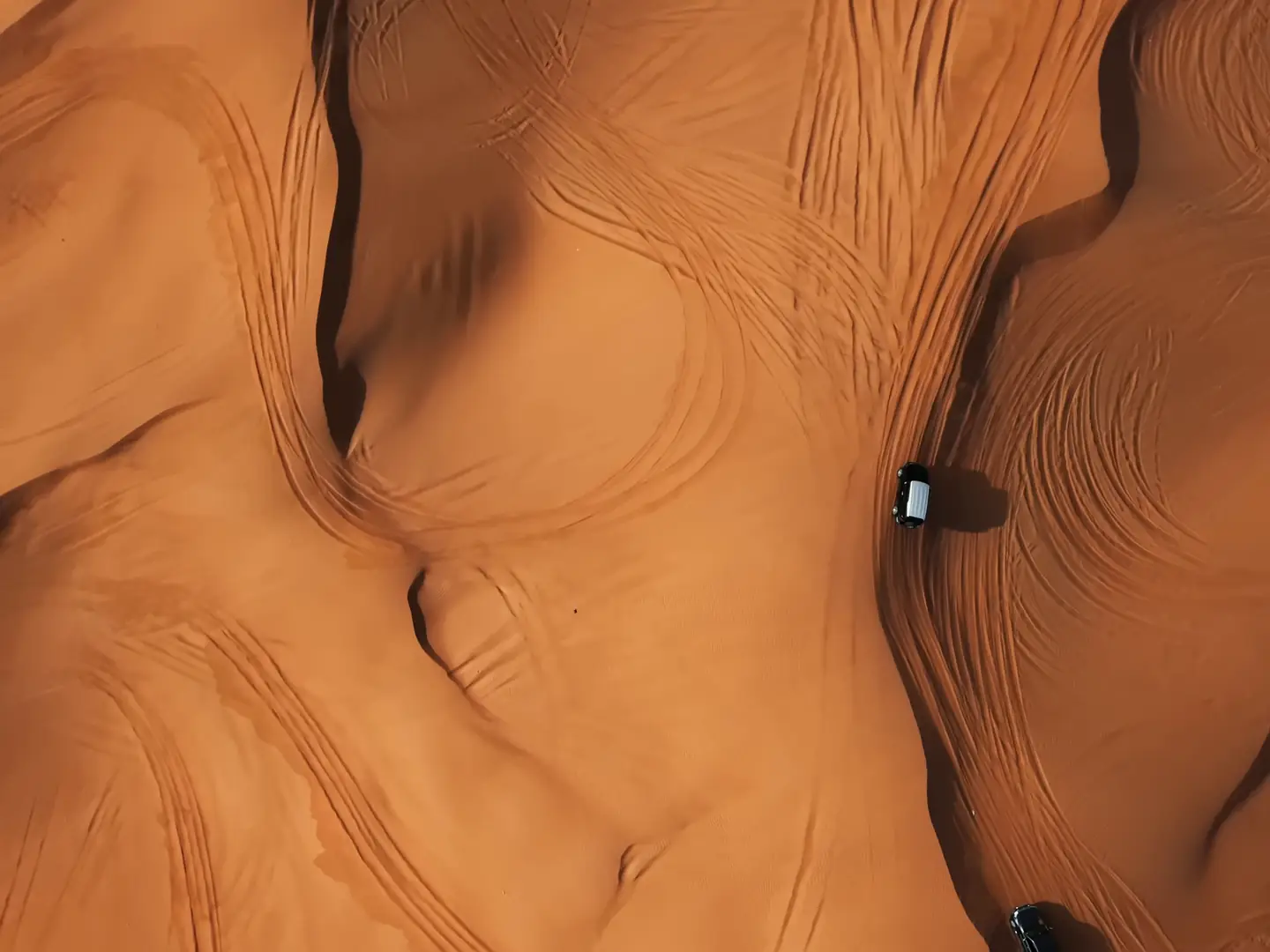 Film of a 4x4 crossing sand dunes seen from above, camels in the desert, Arabic coffee poured into a dallah, and the sun setting over the dunes