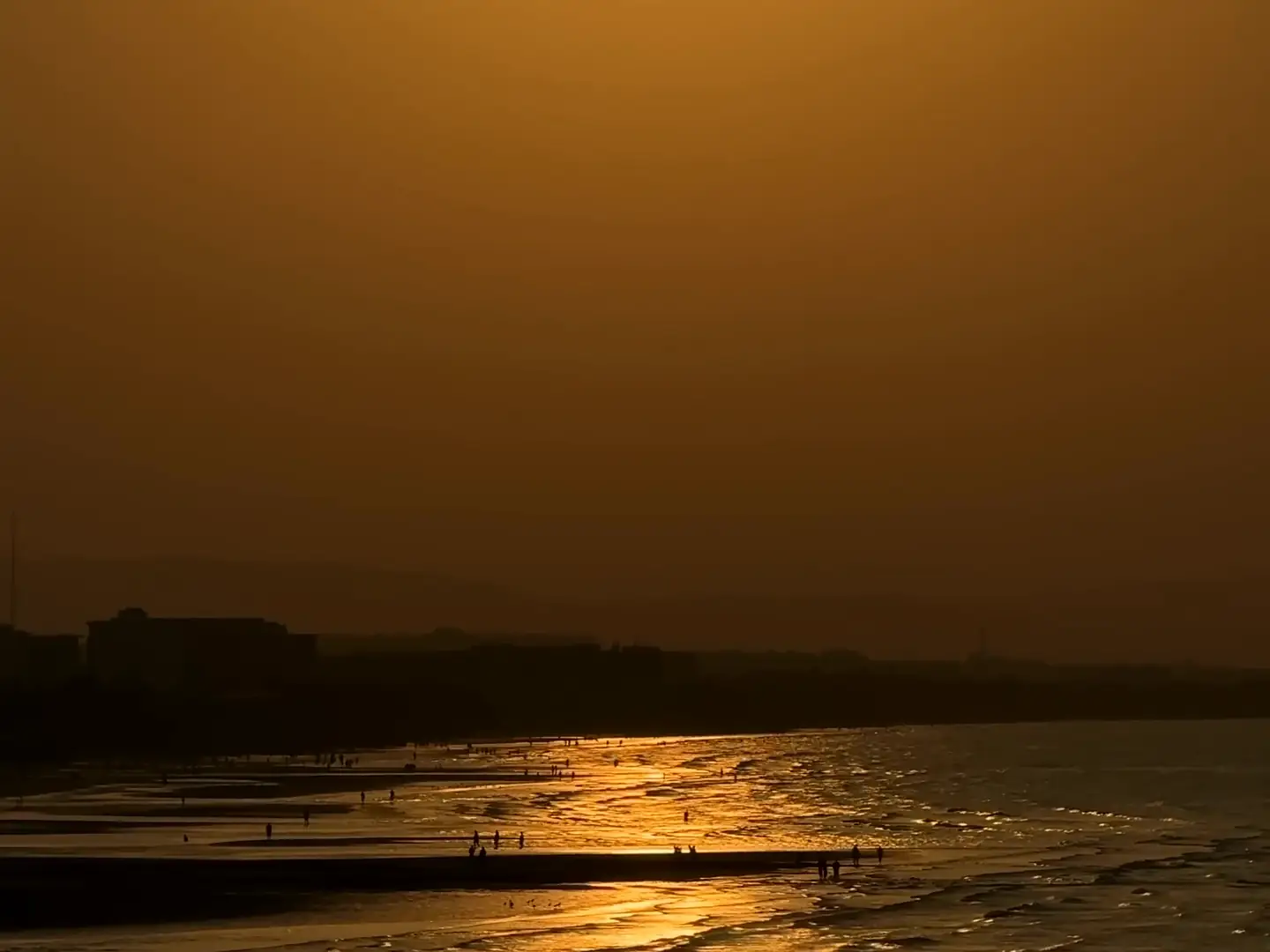 Film of the sun setting over the sea on the Oman coast, its golden reflection on the wet sand, then gentle waves at dusk
